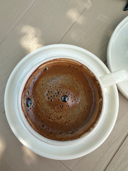 Free A steaming cup of authentic Turkish coffee in a white cup on an outdoor table, casting soft shadows. Stock Photo
