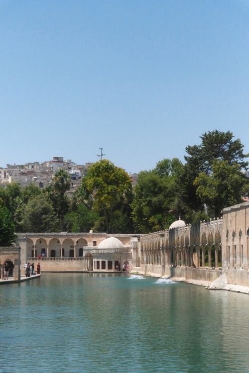 Free Serene landscape with historic architecture by a tranquil pool, surrounded by lush greenery. Stock Photo