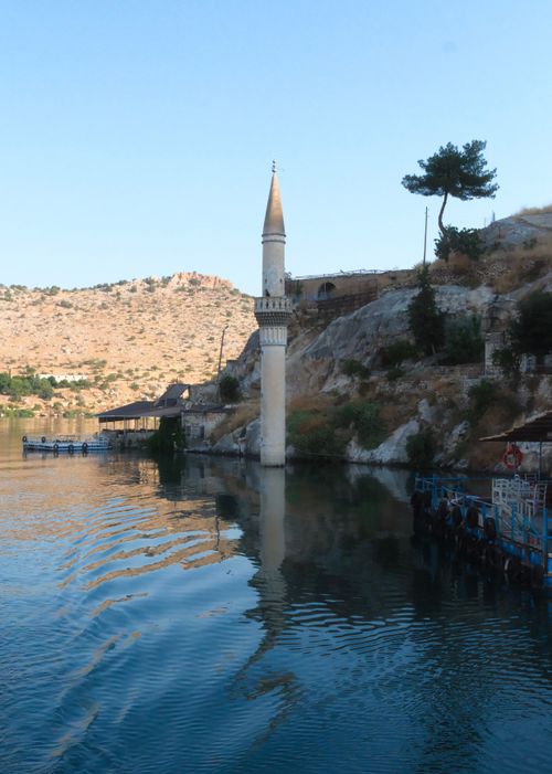 Free Tranquil landscape featuring a submerged minaret by a lakeside with rocky hills. Stock Photo