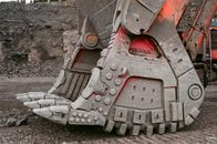 Modern mining loader bucket for lifting heavy loads located on ground in quarry against gray stone wall on daytime