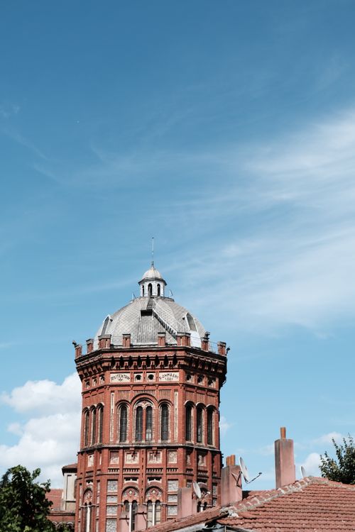 Free A striking view of a historic red brick tower set against a clear blue sky, showcasing architectural beauty. Stock Photo