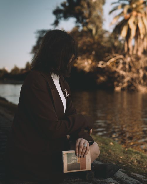 Free A woman enjoys reading by a tranquil riverside in Buenos Aires, Argentina. Stock Photo