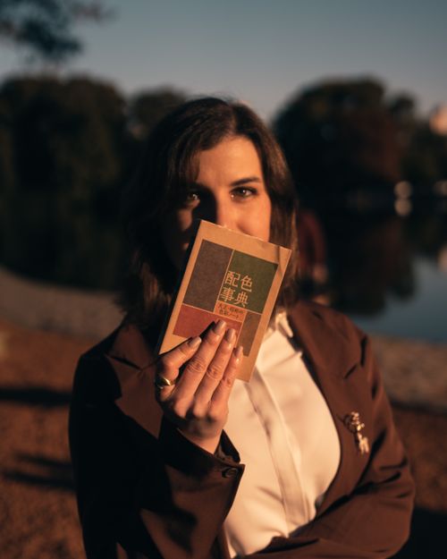 Free A woman in Buenos Aires holds a booklet near a scenic lake during sunset. Stock Photo