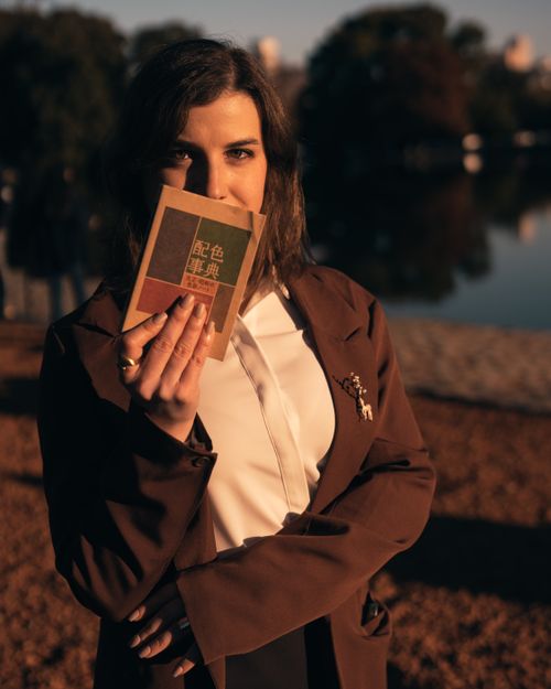 Free A woman holding a book beside a lake in Buenos Aires during sunset, creating a serene mood. Stock Photo