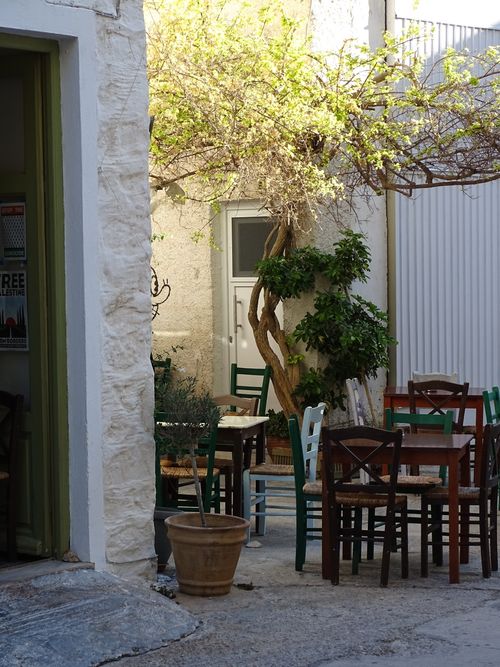 Free Outdoor cafe scene with wooden tables and chairs under a tree in a quaint setting. Stock Photo