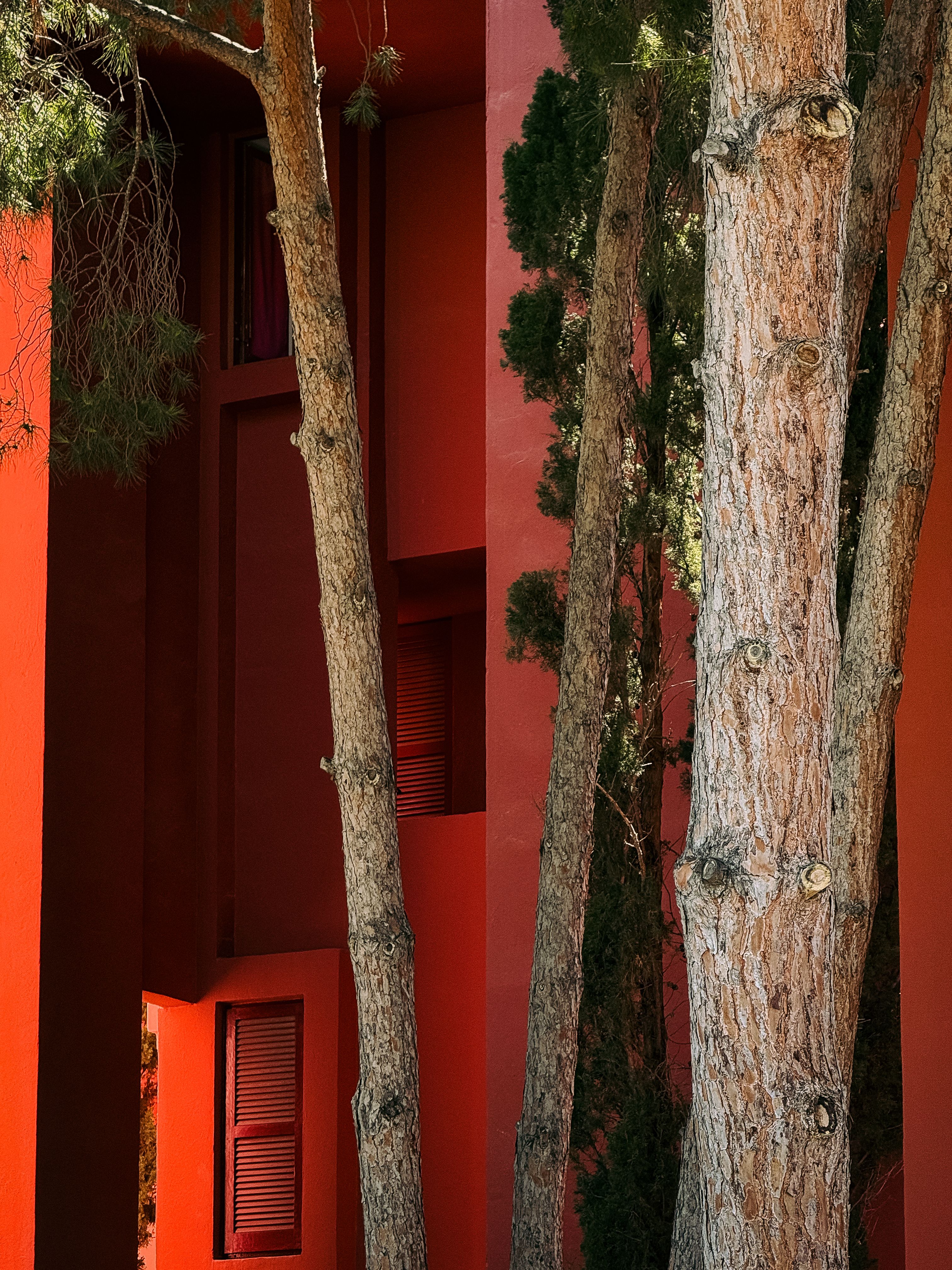 Bold red architecture with vertical trees at La Muralla Roja in Calp, Spain, captures a unique artistic style.