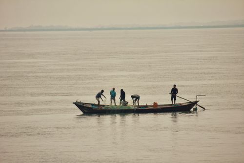 Free Fishermen on a boat casting nets in a serene river in Bangladesh. Stock Photo