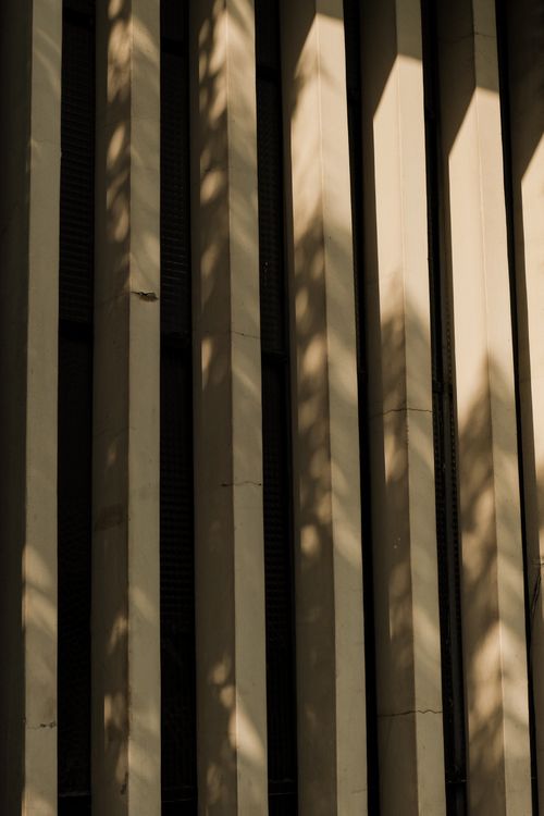 Free Bold shadows create an abstract pattern on modern vertical architecture, showcasing light and shadow interplay. Stock Photo