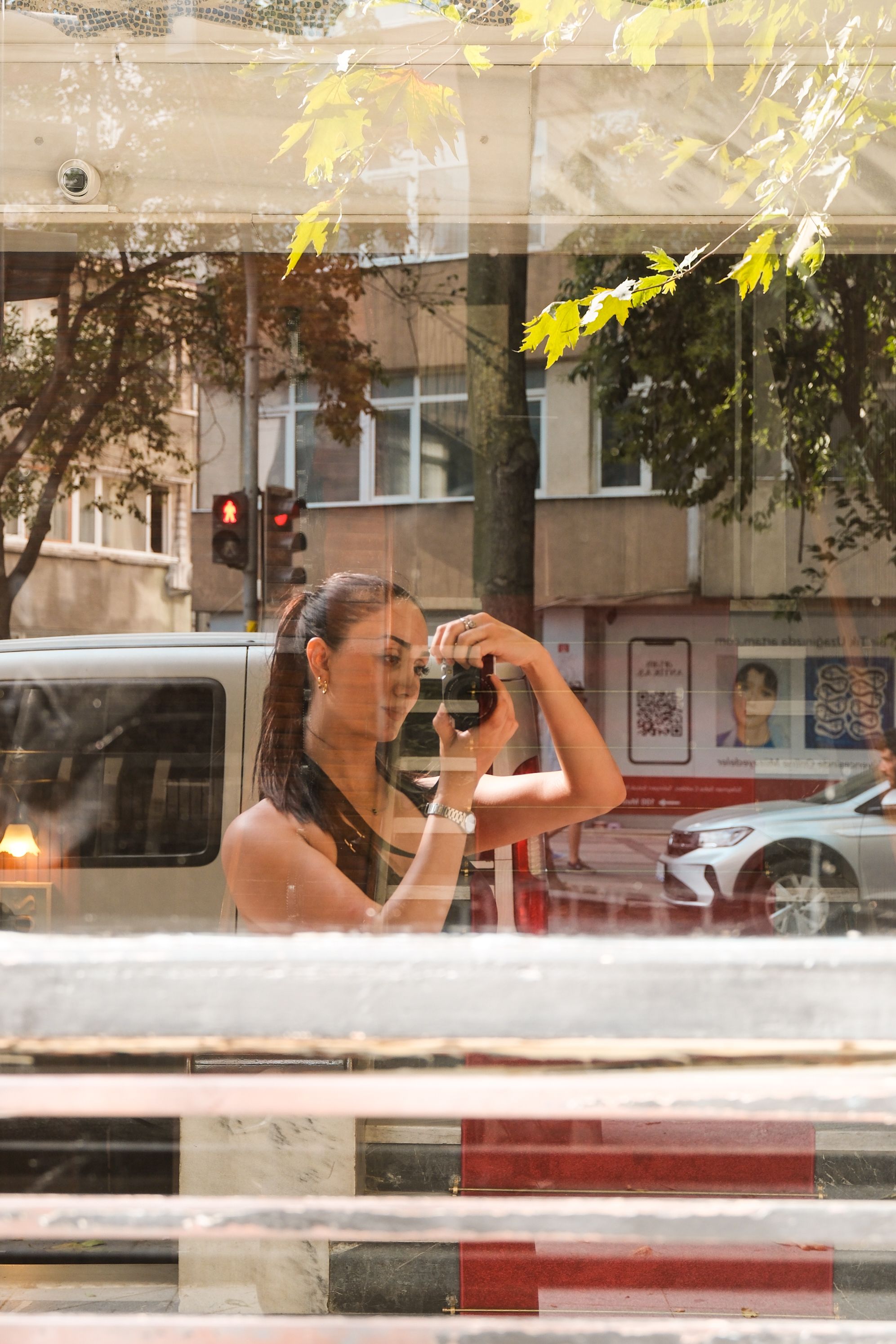 Woman capturing her reflection in a city window, showcasing urban life.