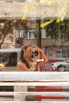 Woman capturing her reflection in a city window, showcasing urban life.