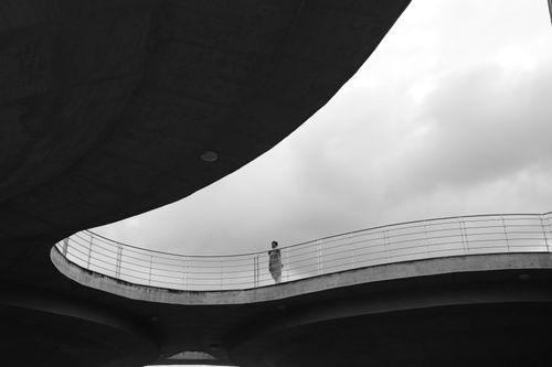 Free Black and white image of a person on a modern concrete structure under cloudy sky. Stock Photo