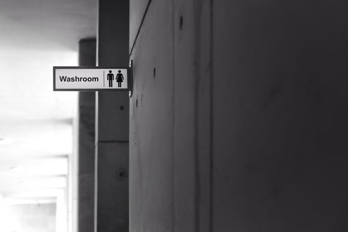 Free Black and white photo of a washroom sign in a minimalist indoor setting. Stock Photo
