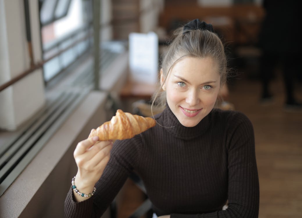 Woman In Black Long Sleeve Shirt Holding Bread