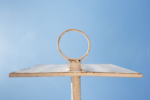 A minimalist basketball hoop with a white backboard set against a clear blue sky, captured from below.