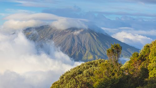 Free A stunning mountain landscape with clouds wrapping around its peak, creating a serene and ethereal scene. Stock Photo