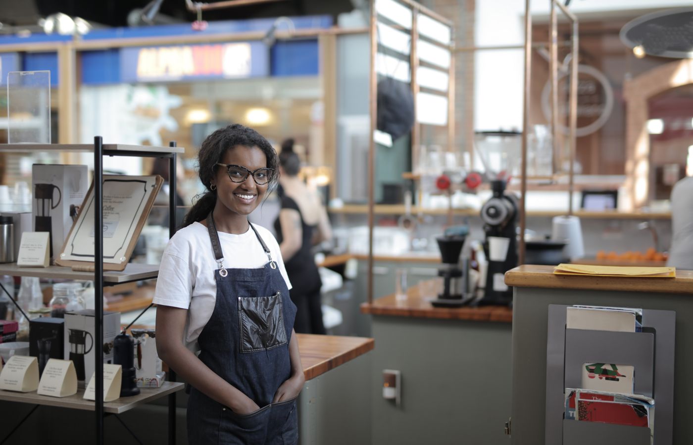 Smiling barista standing in a stylish café, showcasing entrepreneurial spirit.