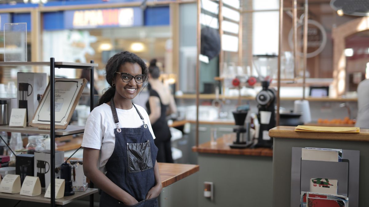 No Longer Self Employed Checklist No longer self employed: a café worker in an apron standing by shelves, ready for a new salaried role