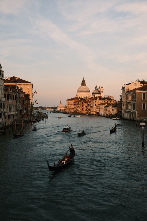 Free Gondolas gracefully glide through the historic Grand Canal in Venice, Italy, during a picturesque sunset. Stock Photo