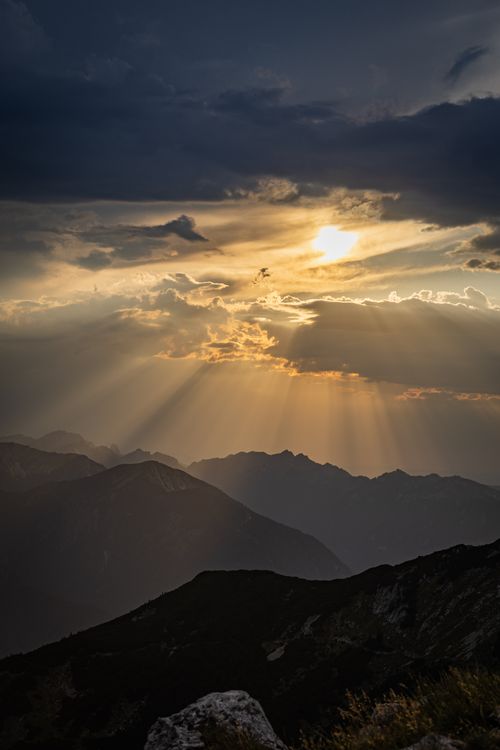 Free Golden sunset casting rays over a serene mountain landscape. Stock Photo