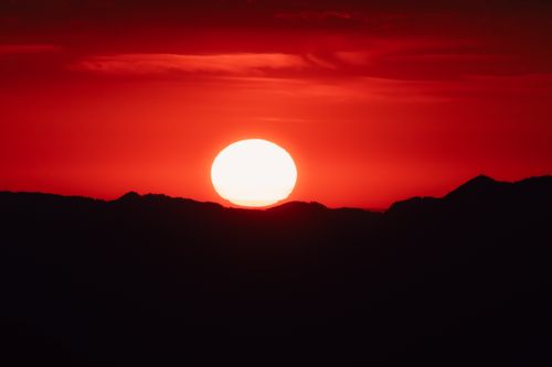 Free A vivid sunset casting a red hue over mountain silhouettes, creating a dramatic scene. Stock Photo