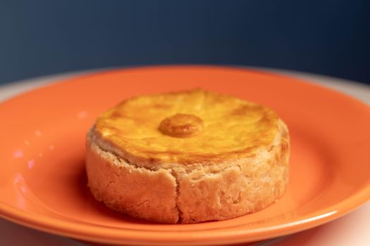 Close-up of a homemade quiche served on an orange plate, showcasing a classic savory pastry.