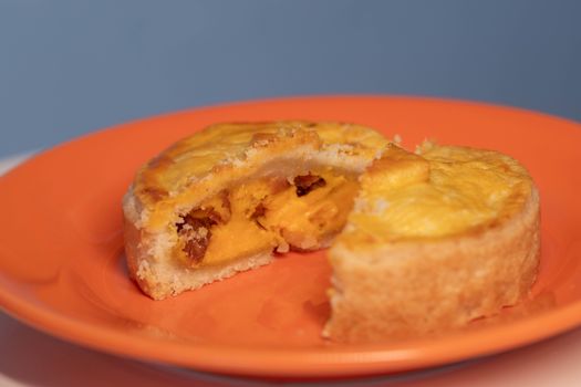 Close-up of a sliced mango tart on a bright orange plate, showcasing its rich, fruity filling.
