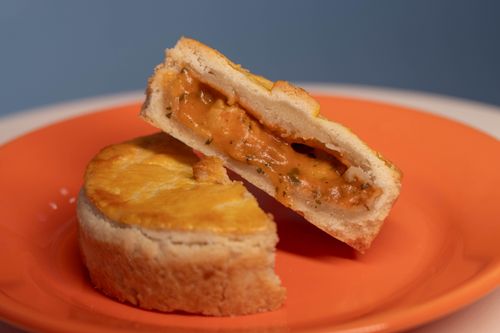Free A delicious creamy cheese pie cut in half, served on a vibrant orange plate against a blue background. Stock Photo