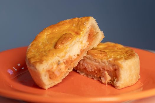 Close-up of a delicious, freshly baked chicken pie cut open to reveal savory filling, served on an orange plate.