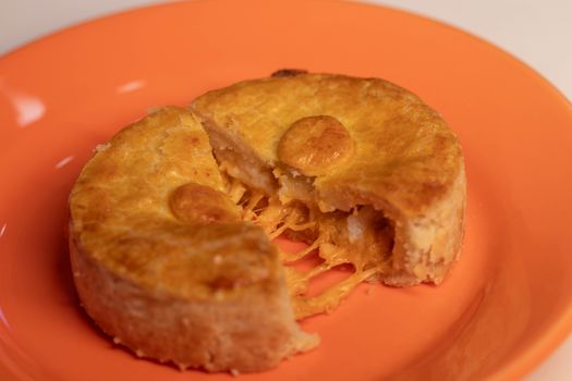 A delicious golden cheese pie served on a bright orange plate.