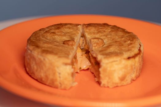 Golden-brown chicken pot pie with savory filling served on an orange plate.