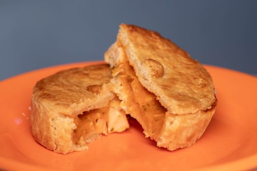 Close-up of a savory chicken pie with golden crust on an orange plate.