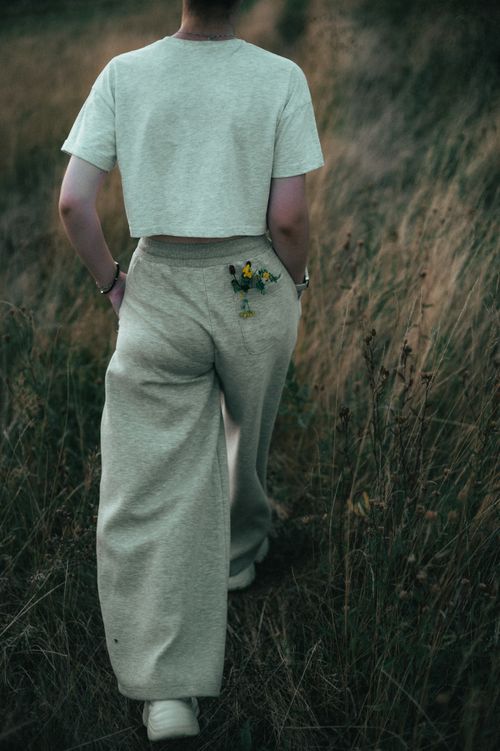Free Person walking in a meadow during sunset, wearing casual fashion. Stock Photo
