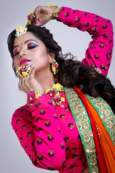 在室内，一位充满活力的印度妇女身着传统服装，搭配花卉配饰，妆容色彩缤纷，优雅地摆着姿势