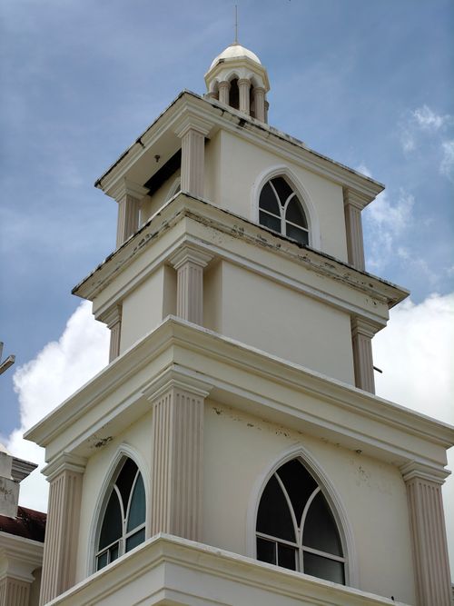 Free A colonial-style church tower with arched windows against a vibrant blue sky. Stock Photo