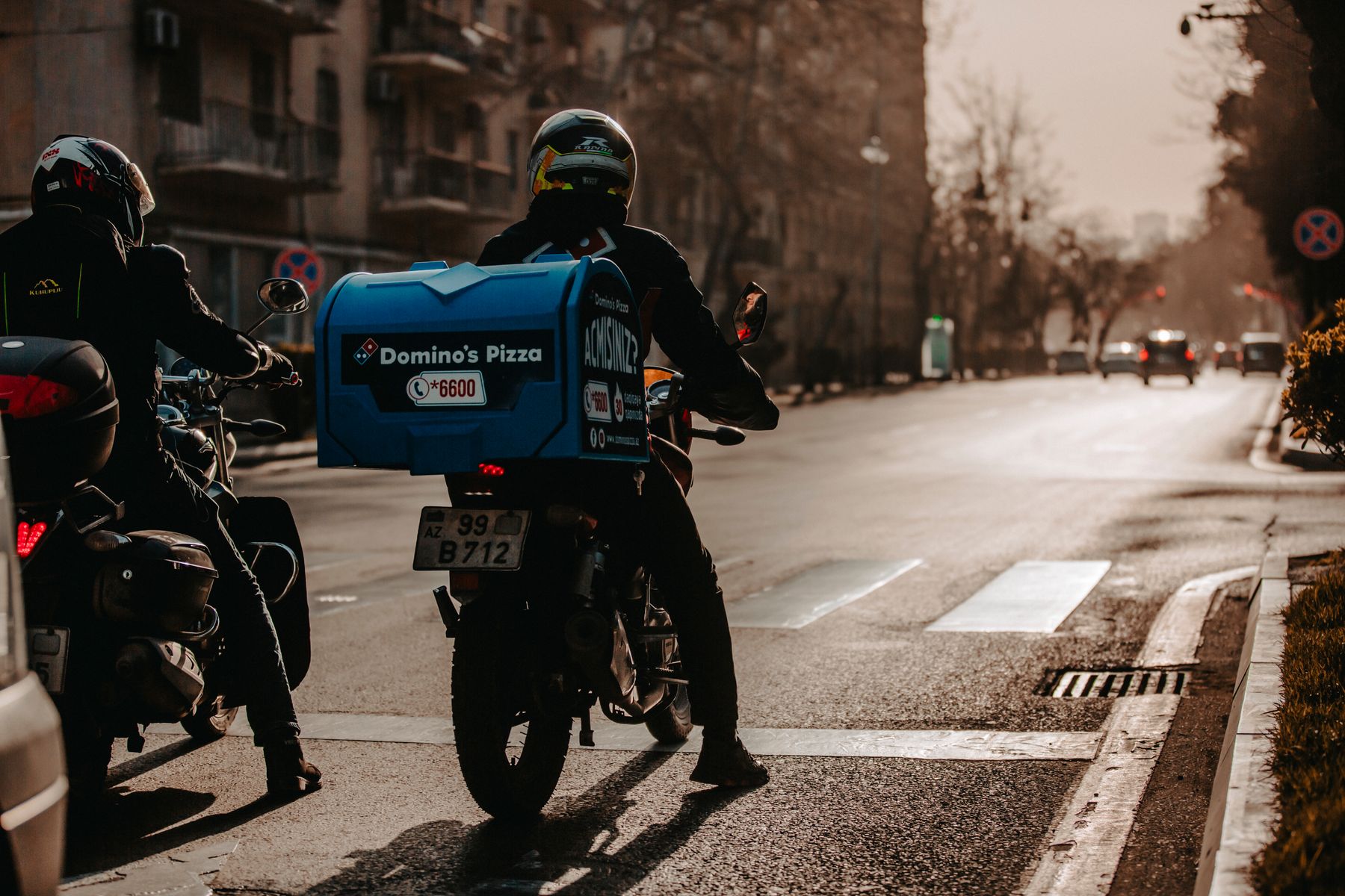Şehir sokağında paket taşıyan motorlu kurye