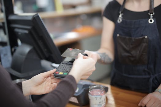 Close-up of customer and cashier during a credit card transaction at a store counter indoors.