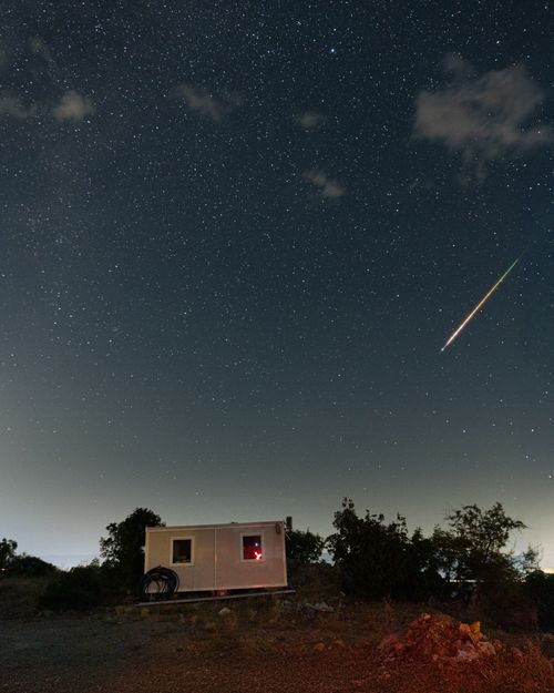 Free A bright meteor streaks across a starry night sky during the Perseid meteor shower. Stock Photo