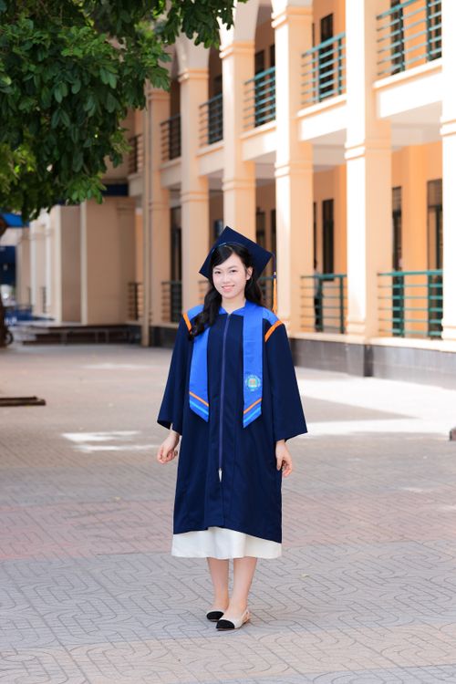 Free Young woman in graduation attire standing on a sunny day at university campus in Hanoi, Vietnam. Stock Photo
