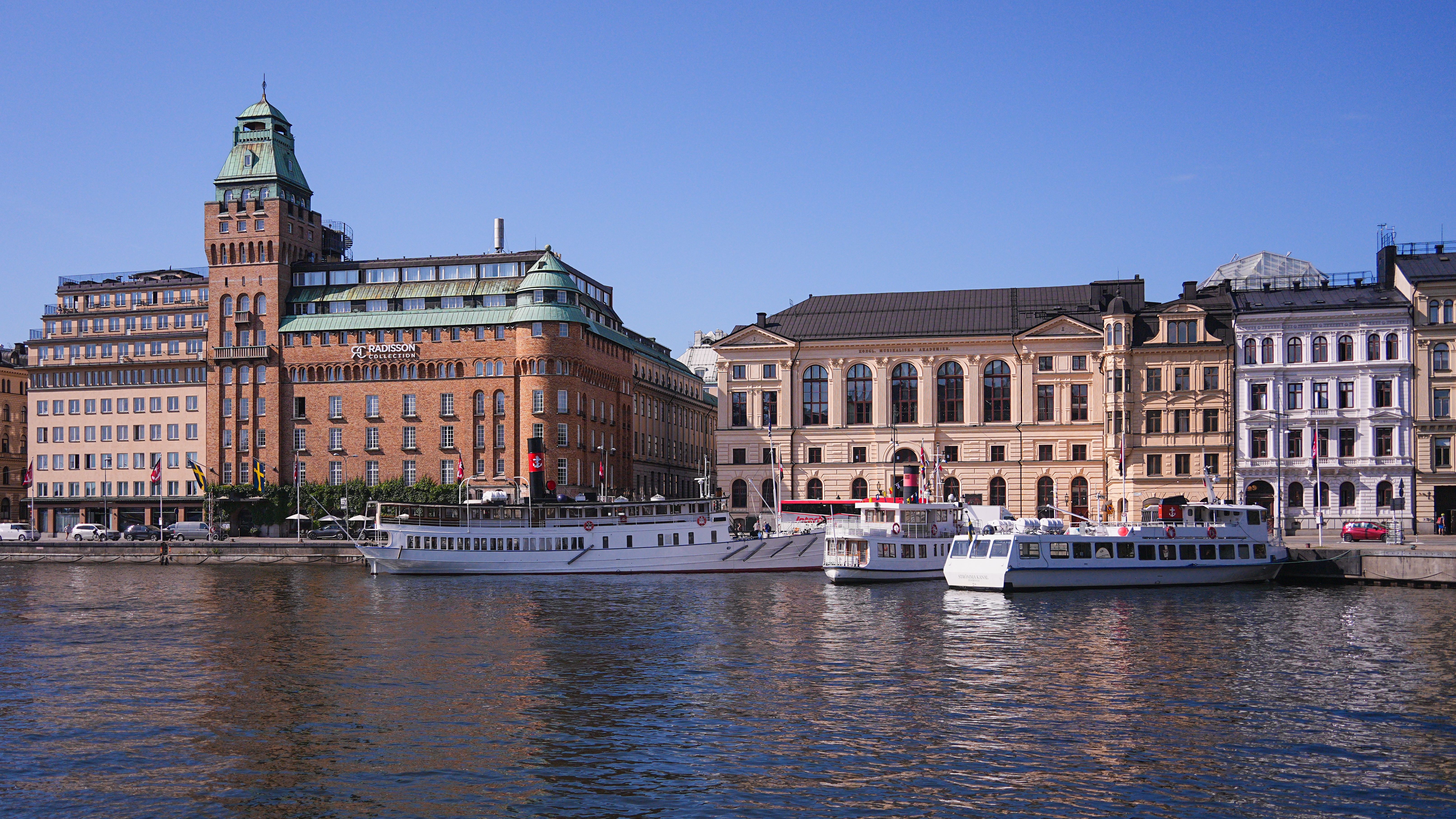 Charming waterfront view of historic buildings and boats in Stockholm's cityscape.