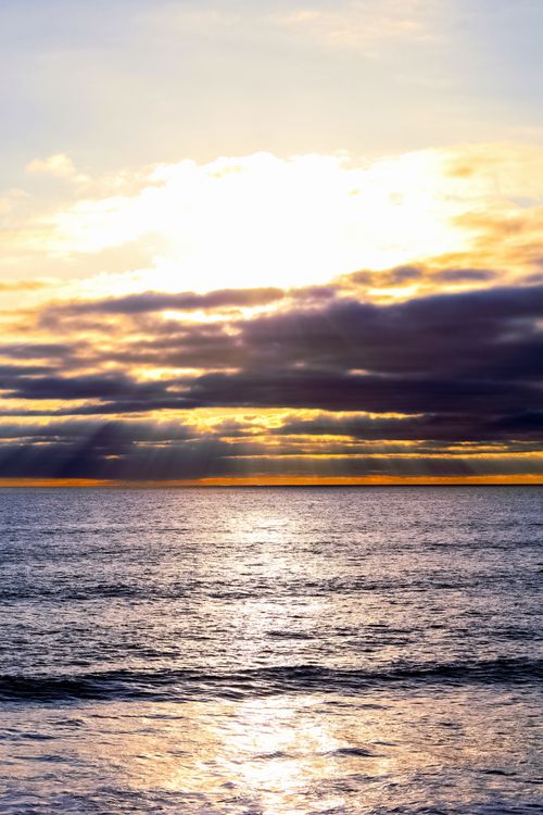 Free Beautiful sunset over the ocean with dramatic clouds and sun rays. Stock Photo