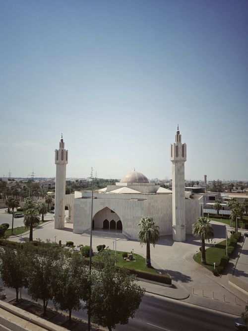 Free Beautiful view of mosque with minarets and dome under clear blue sky, surrounded by palm trees. Stock Photo