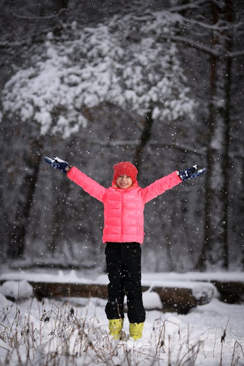 Person In Pink Jacket And Black Pants Standing on Snow Covered Ground