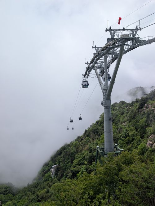 Free Cable cars traveling through misty mountains, surrounded by lush greenery, creating a serene landscape. Stock Photo