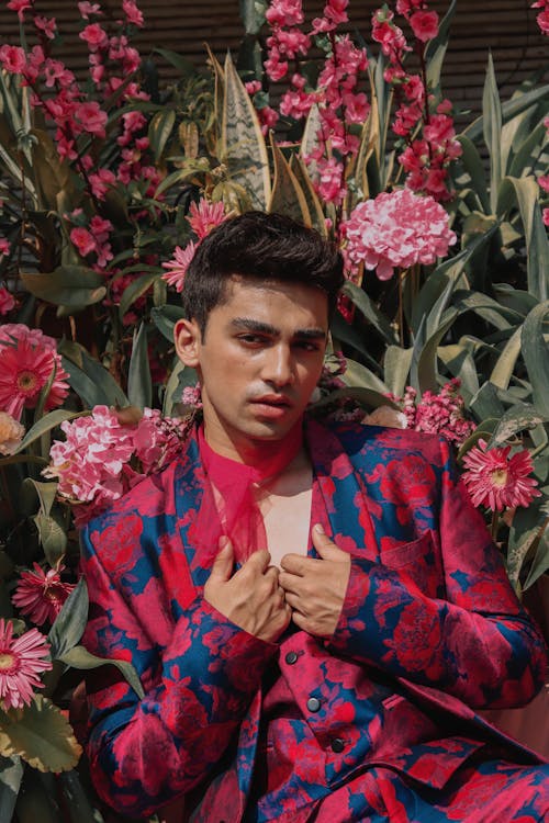 Stylish young ethnic guy with flowers on background