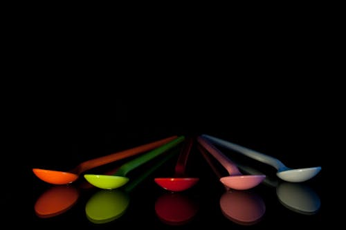 Five Assorted-color Spoons on Black Surface