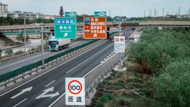 Highway with signs near Jiayuguan, China, showing traffic and travel directions.