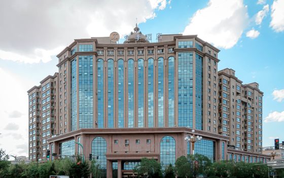 A grand, multi-story hotel building with modern architecture against a clear blue sky.
