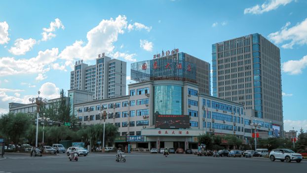 Cityscape featuring modern high-rise buildings and a busy intersection on a sunny day.