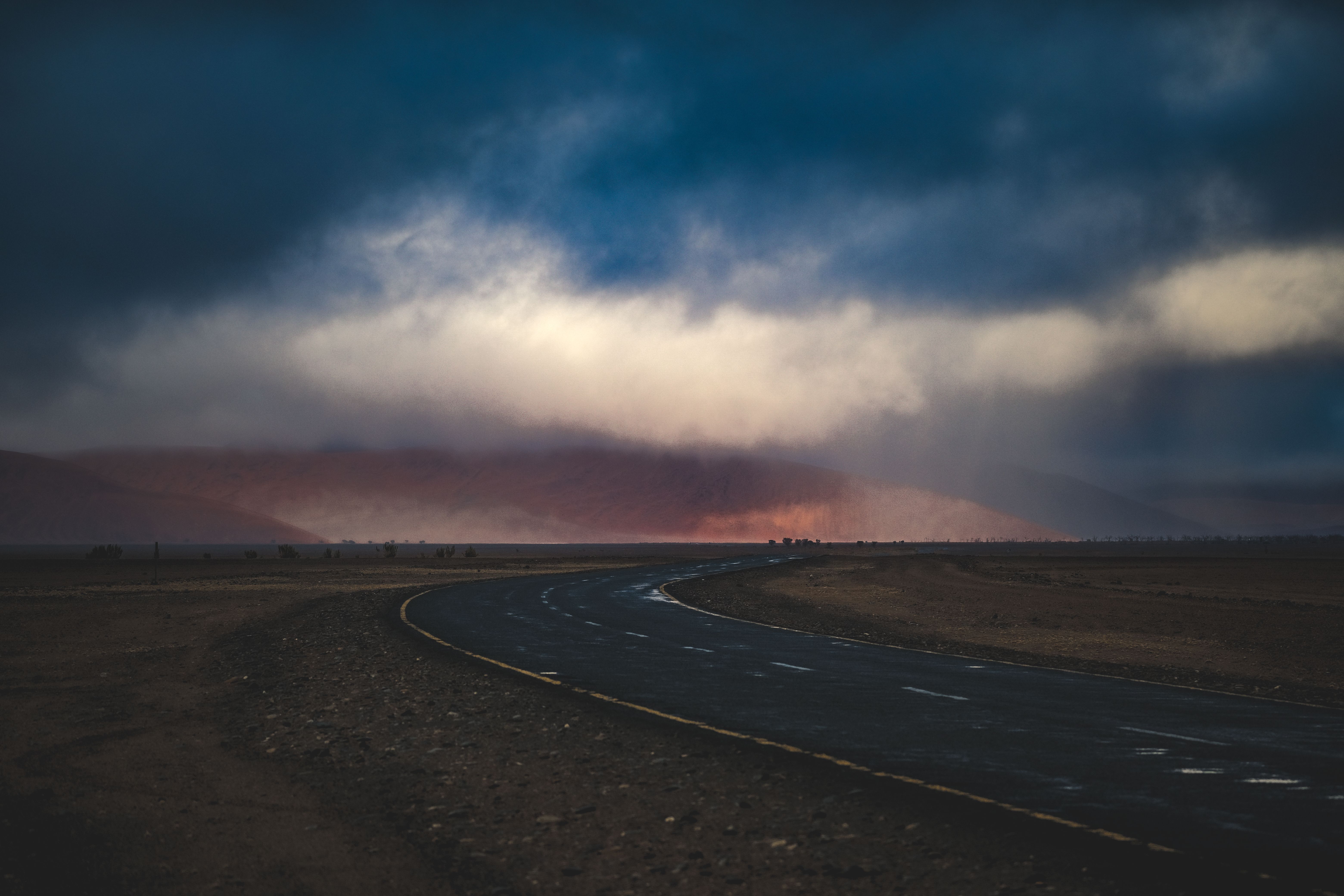 A dark, empty road stretches beneath heavy storm clouds, evoking the cost and danger of shepherding.