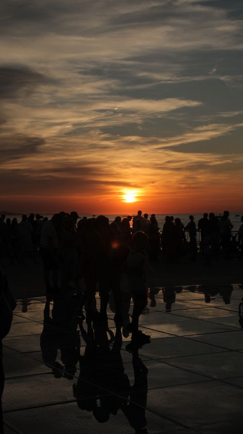 Free A scenic view of people gathered at Zadar's waterfront at sunset, reflecting on the water. Stock Photo